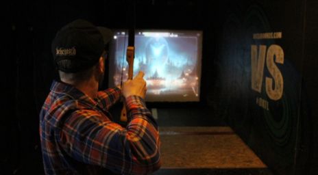 Man standing in front of a digital screen with a bow and arrow